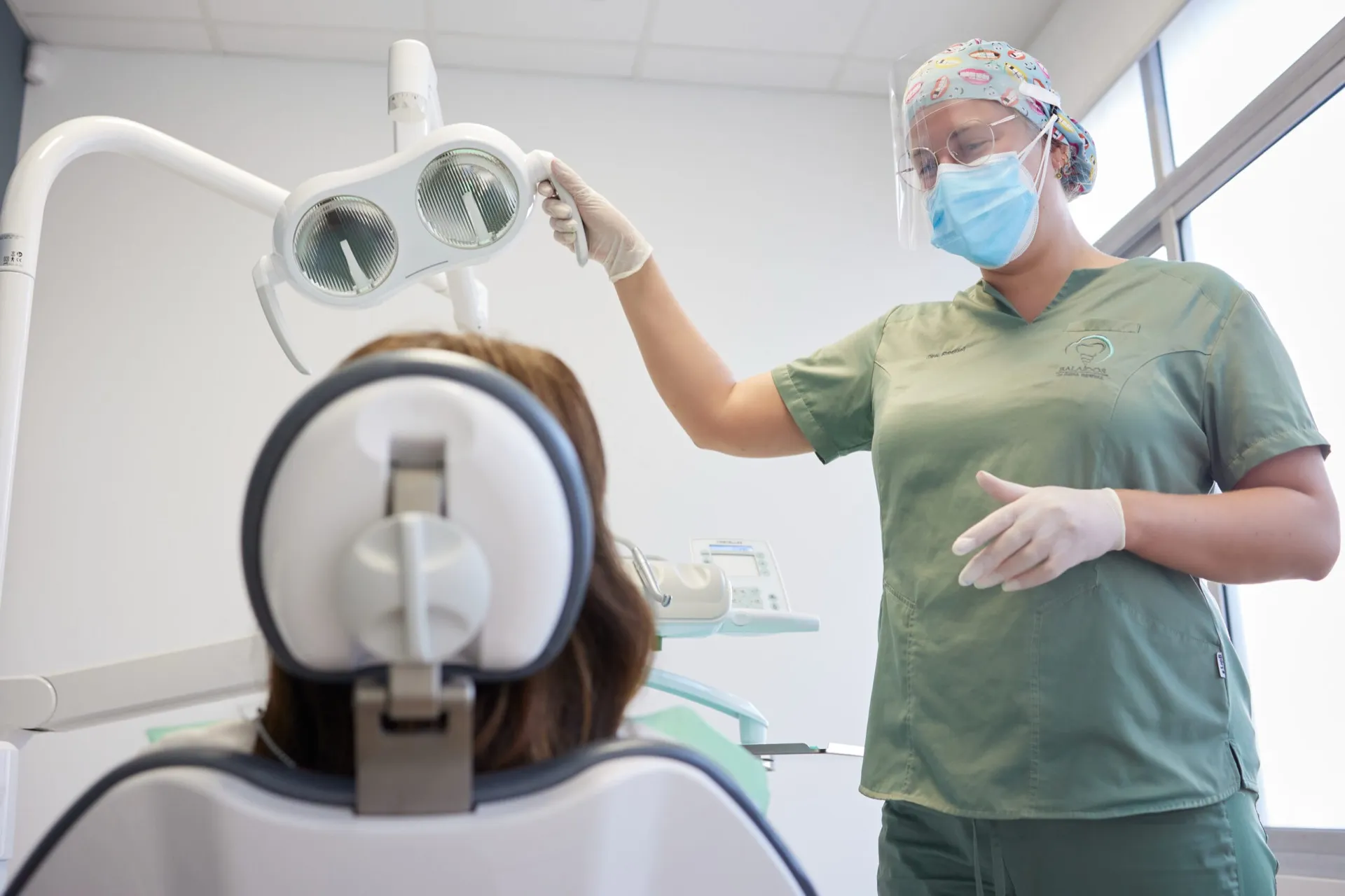 Doctora de Clínica Dental Balaídos ajustando la lámpara del gabinete sobre una paciente