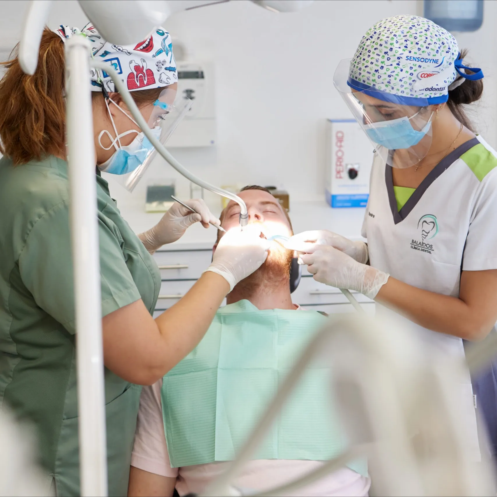 Dos profesionales de Clínica Dental Balaídos atendiendo juntas a un paciente