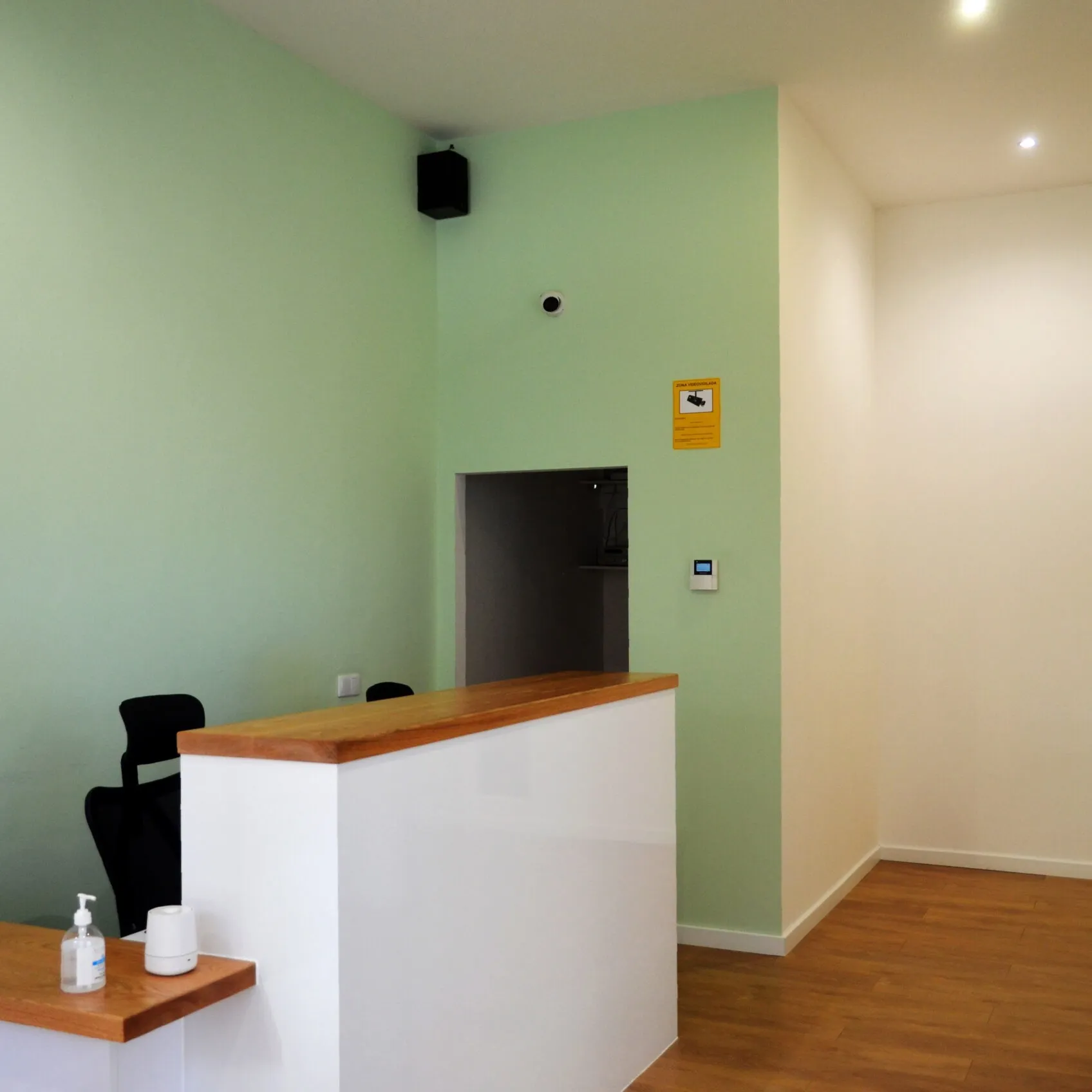 Recepción de Clínica Dental Balaídos, con mostrador de madera y paredes verdes